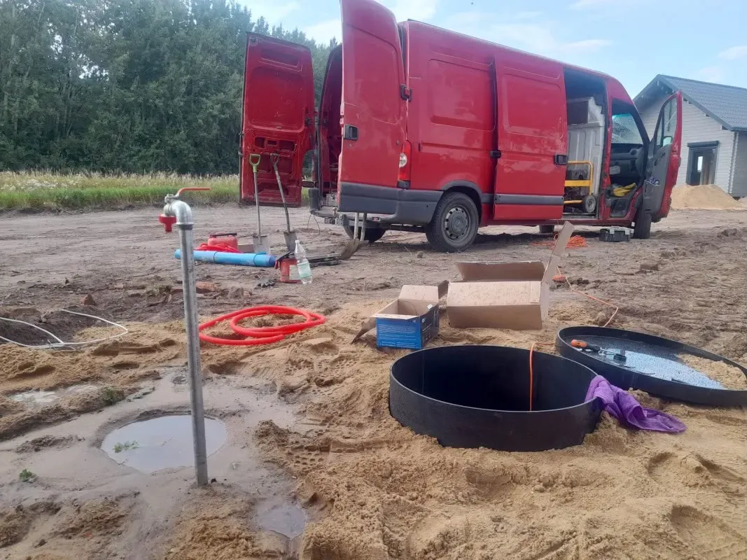 Czerwony bus serwisowy, rura studni i obudowa przygotowana do montażu na działce